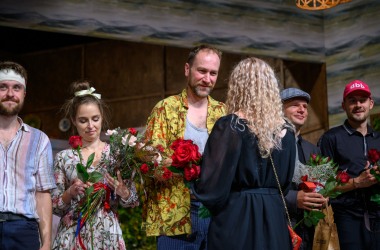 aktorzy dostają kwiaty od kobiety w długich blond włosach, jest trzech aktorów po prawej obok nich młoda aktorka i po lewej młody aktor w bandażu na głowie