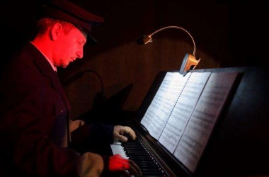 pianista młody mężczyzna gra na pianinie ma przed sobą pulpit z nutami