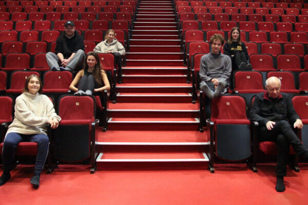 na czerwonych fotelach na dużej scenie siedzi trzy aktorki i reżyserka oraz trzech aktorów uśmiechają się
